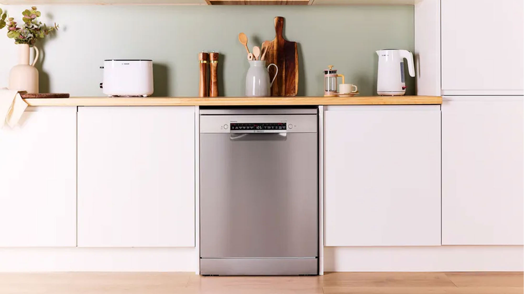 Modern kitchen setup with a stainless steel dishwasher, white cabinets, and countertop appliances including a toaster and kettle.