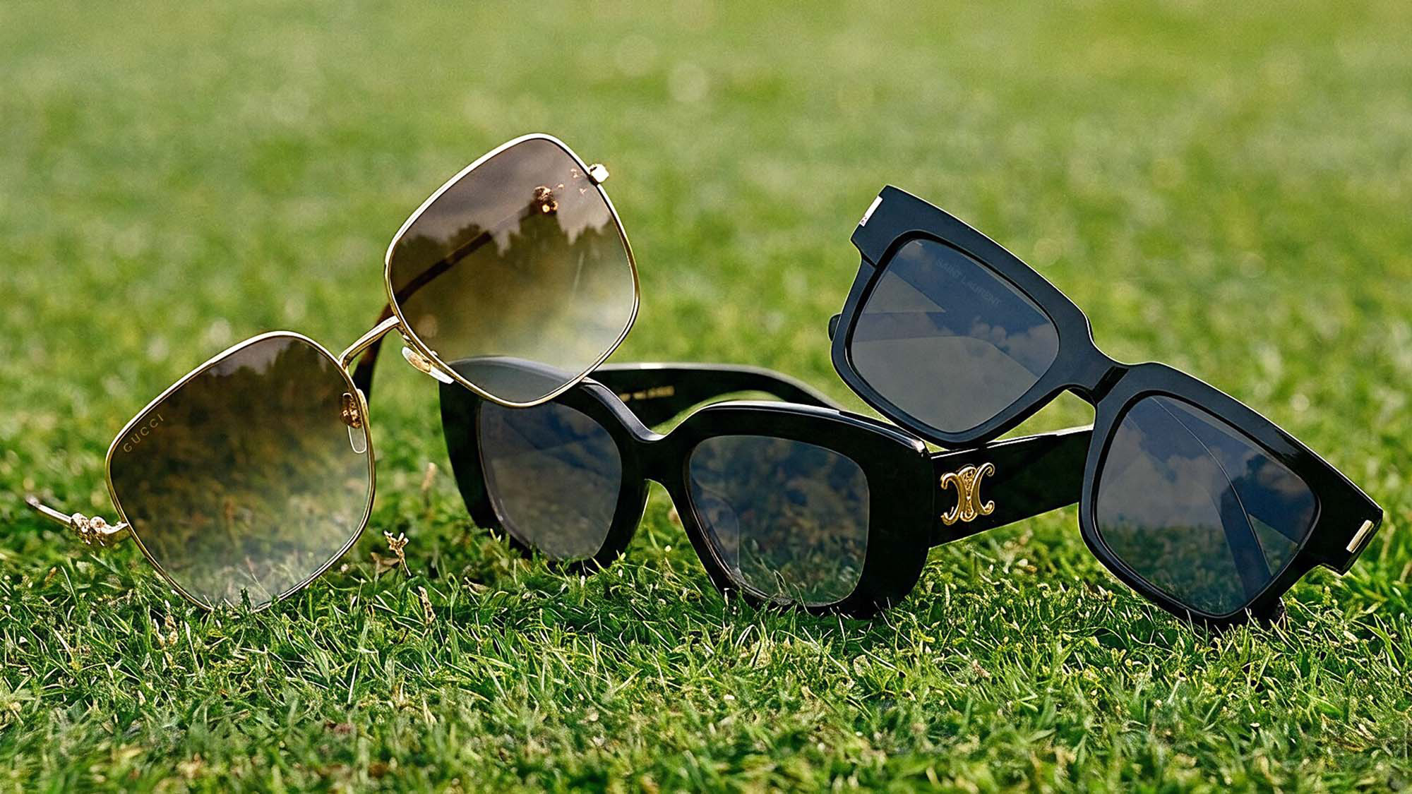 Three pairs of stylish sunglasses on grass.