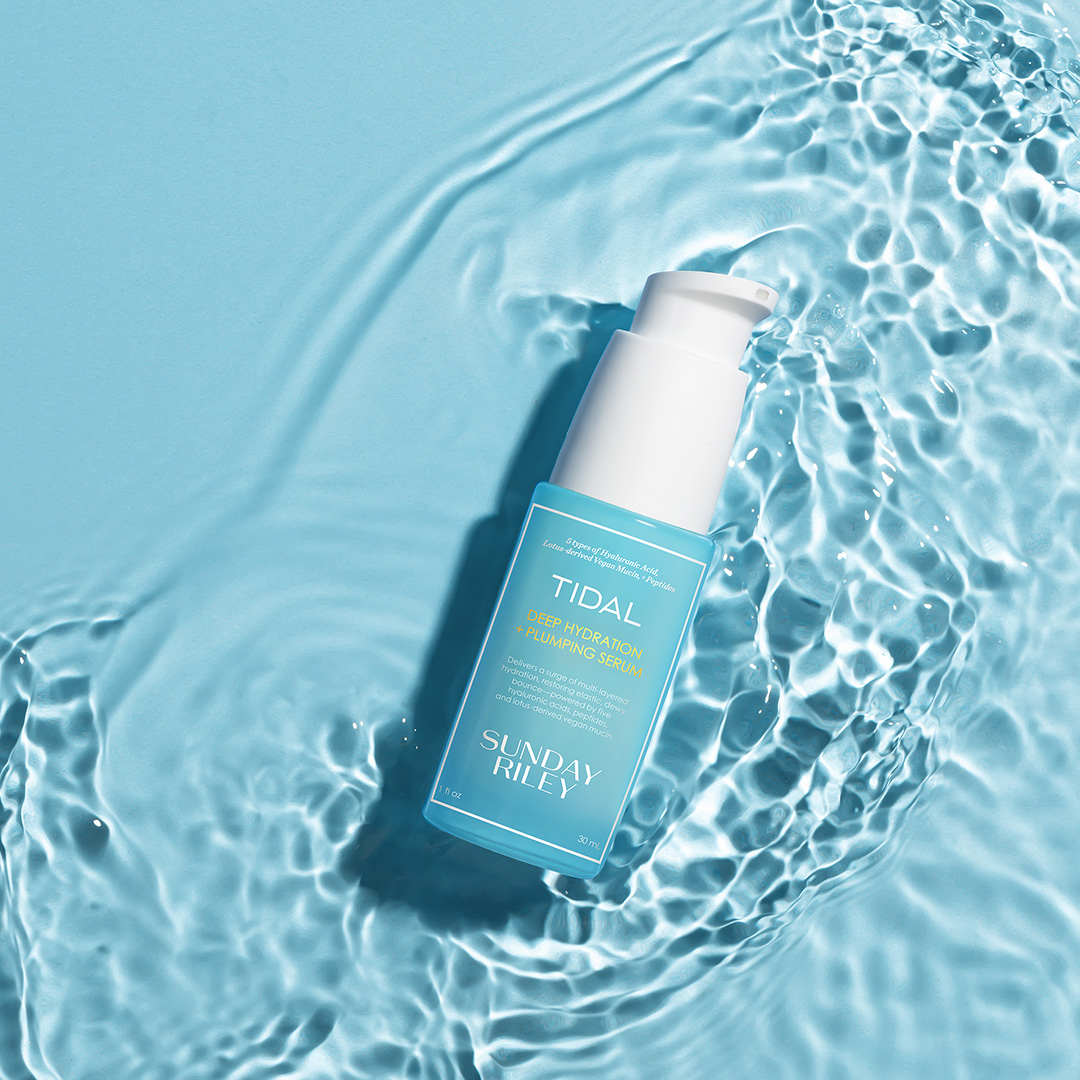 Sunday Riley Tidal Deep Hydration serum bottle on clear blue water with rippling texture background
