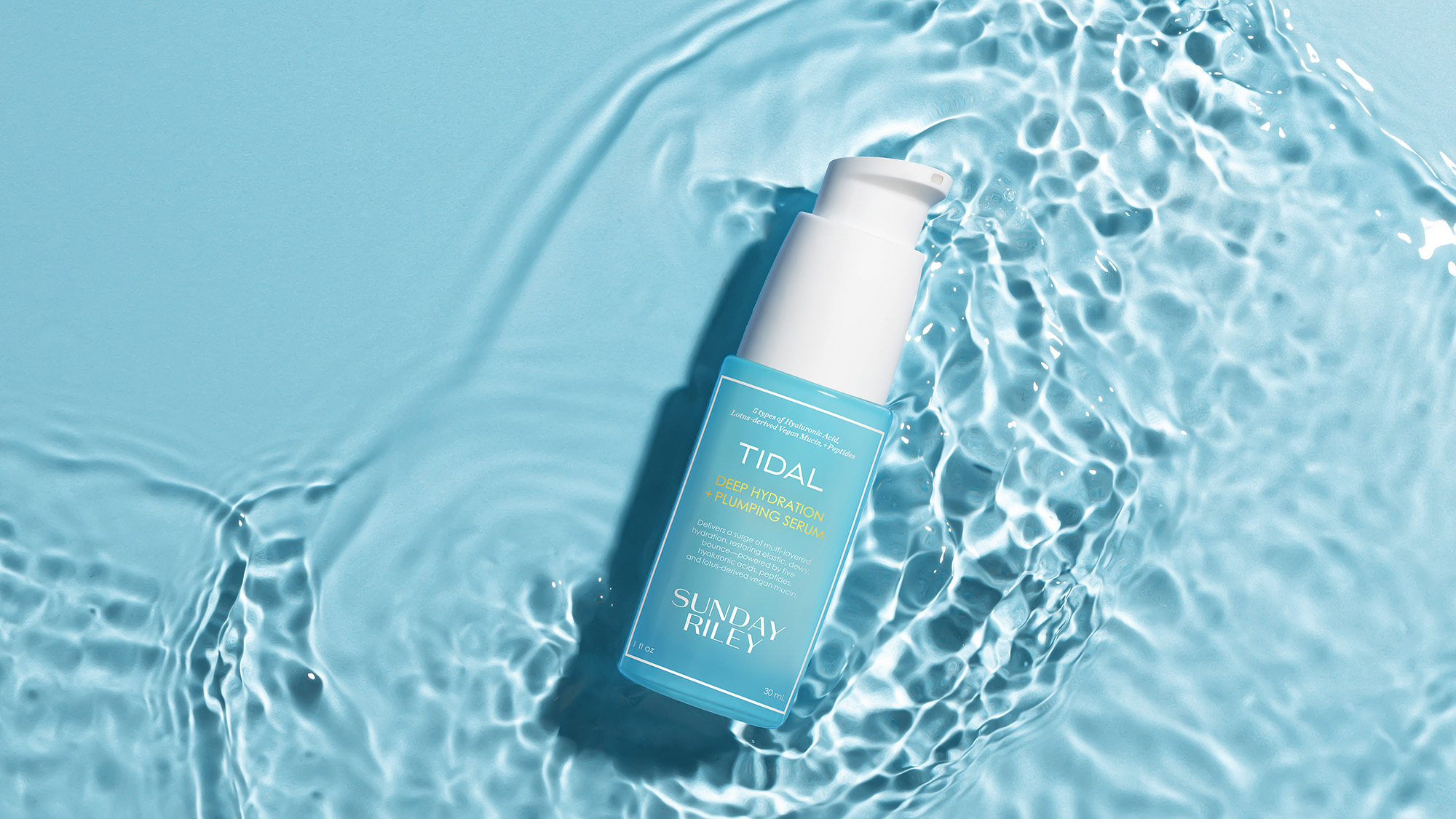 Tidal Deep Hydration Pumping Serum bottle with white cap displayed on shimmering turquoise water surface