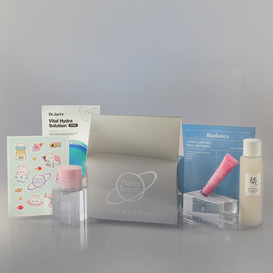 A collection of beauty and skincare products, including a Dr. Jart+ Vital Hydra Solution sheet mask, Biodance Hydro Cream Mask, various cosmetics in bottles and tubes, a pink jar, and a packet of cartoon stickers. The items are displayed against a minimalist background.
