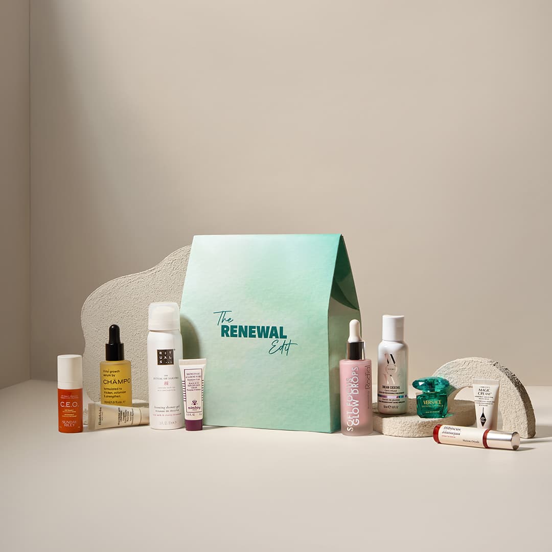 A collection of skincare and beauty products arranged around a green box labelled 'The Renewal Edit'. Products include serums, creams, and oils displayed on a minimalist backdrop with soft lighting.
