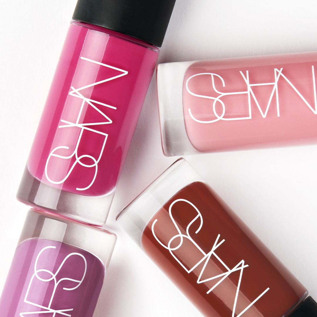 NARS lip and nail products in shades of pink and burgundy with white outline branding