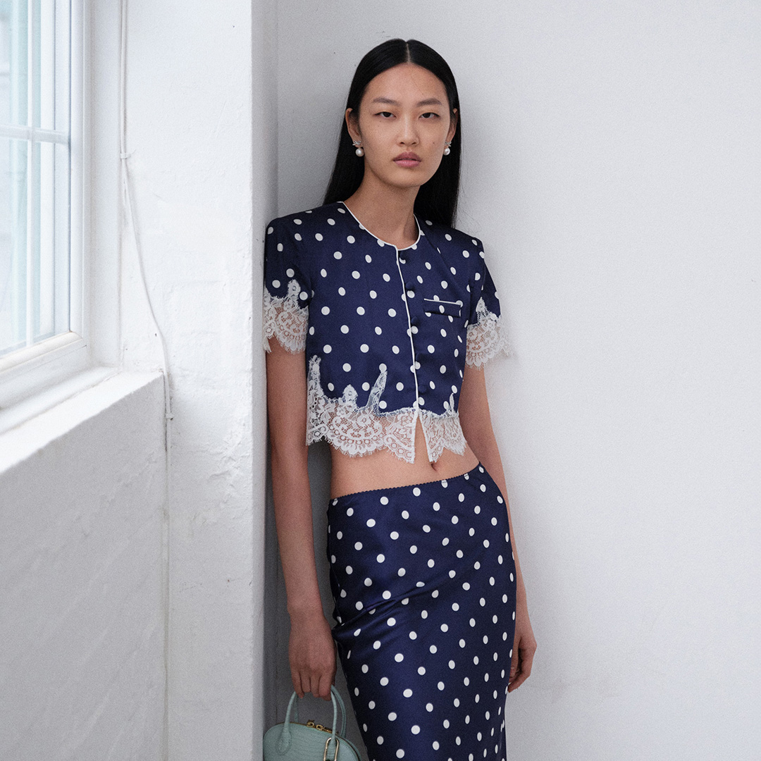 Woman wearing navy polka dot crop top with lace trim and matching maxi skirt