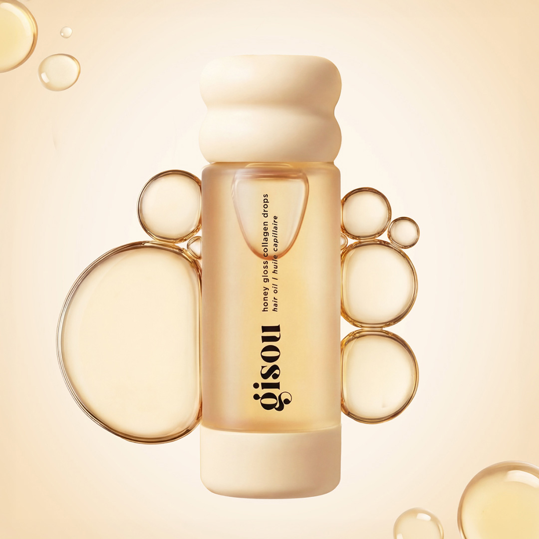 Gisou honey gloss collagen drops hair oil bottle surrounded by golden droplets and bubbles