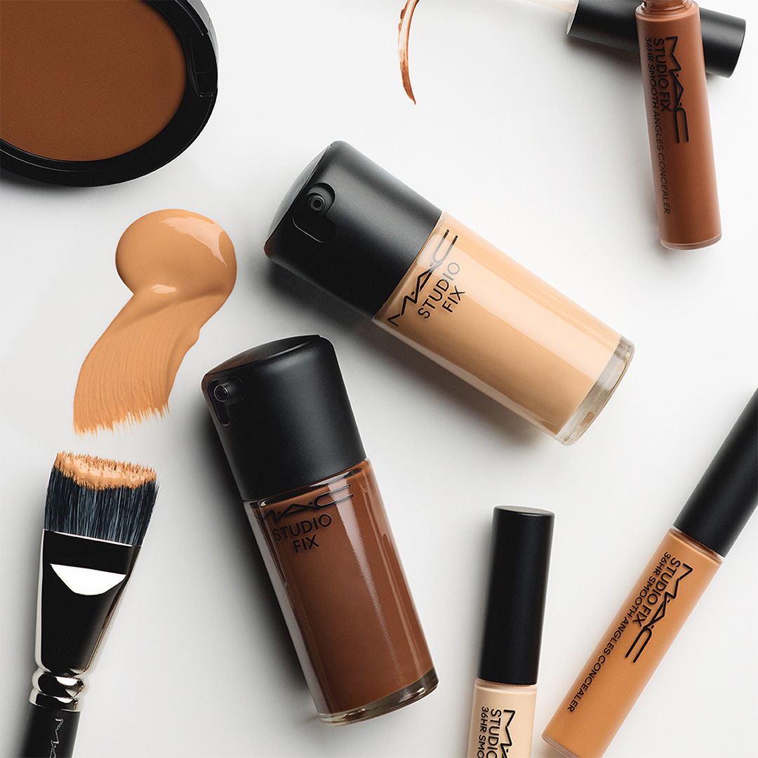 Collection of face makeup products including foundation, powder, and concealer in warm tan and bronze tones with application swatches