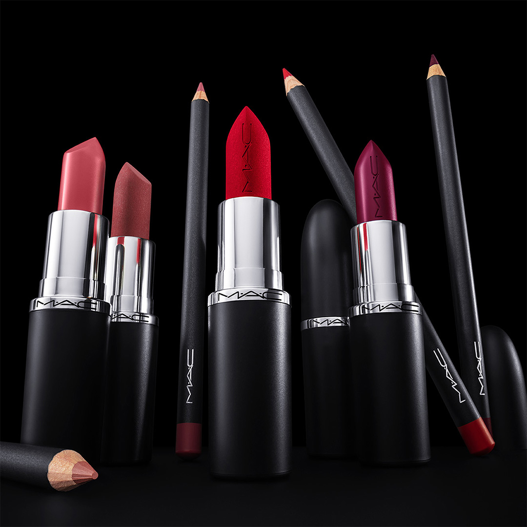 Range of lipsticks and lip pencils in pink, red, and burgundy shades with matching eyeliners displayed against black background