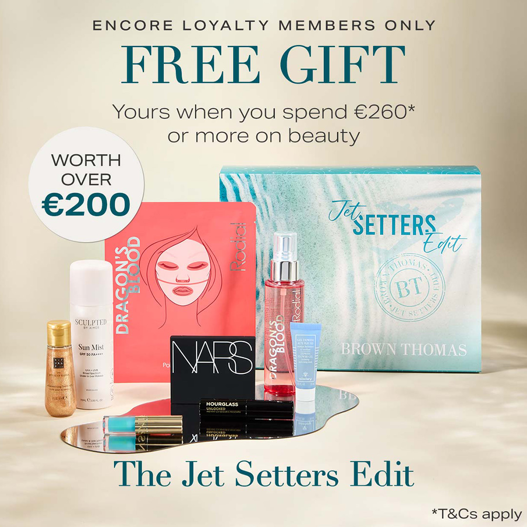 Curated beauty gift set with branded boxes, cosmetics, and skincare products displayed on reflective surface, Jet Setters Edit packaging