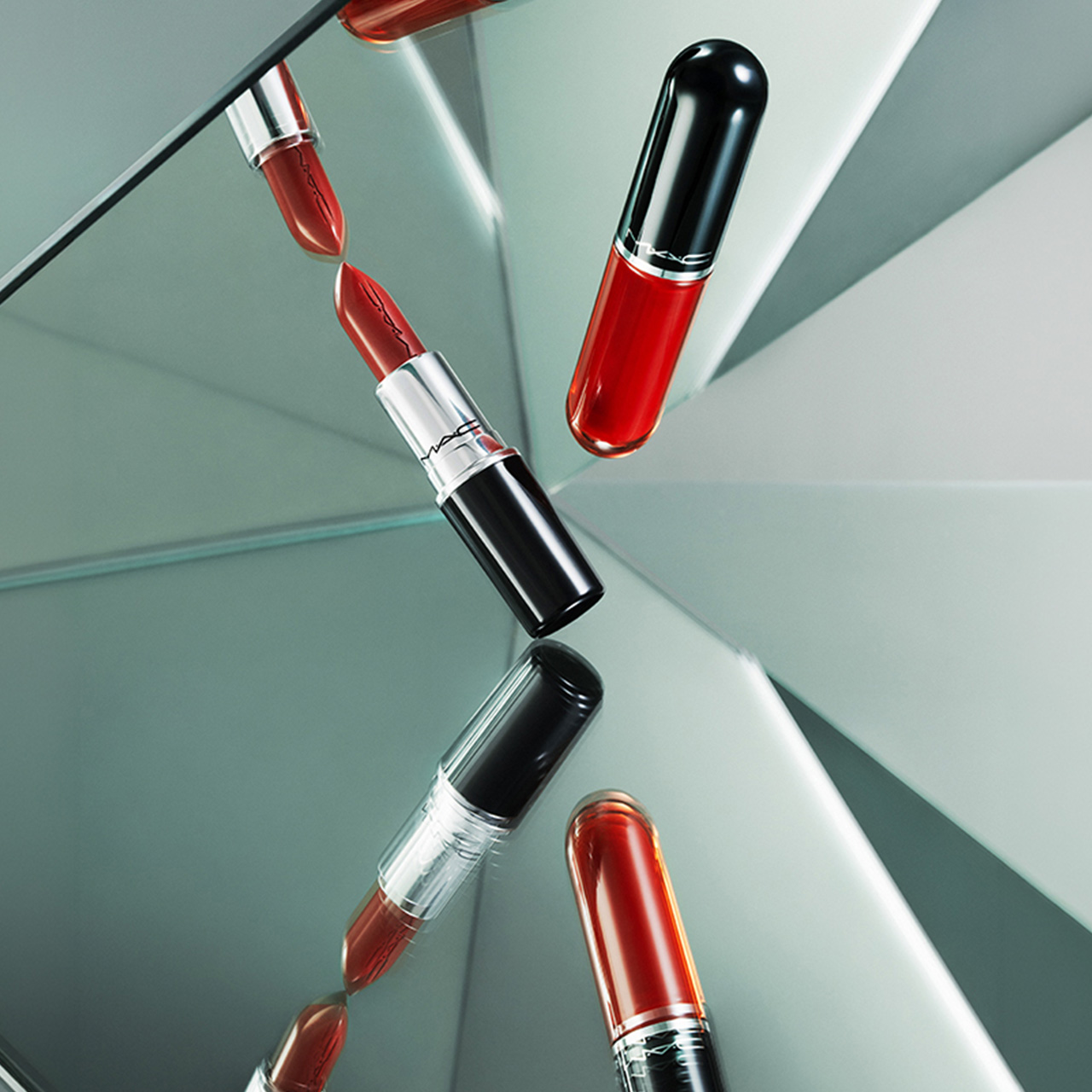 M.A.C Lustreglass lipsticks in red shades arranged on geometric mint green surface