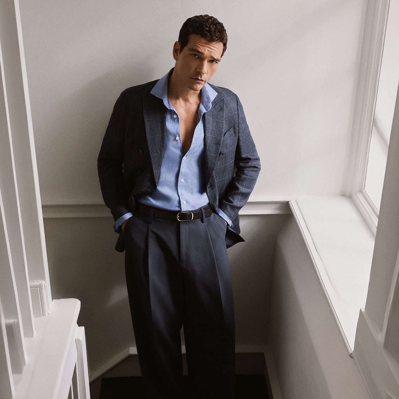 Man wearing charcoal blazer over blue shirt with navy trousers and belt