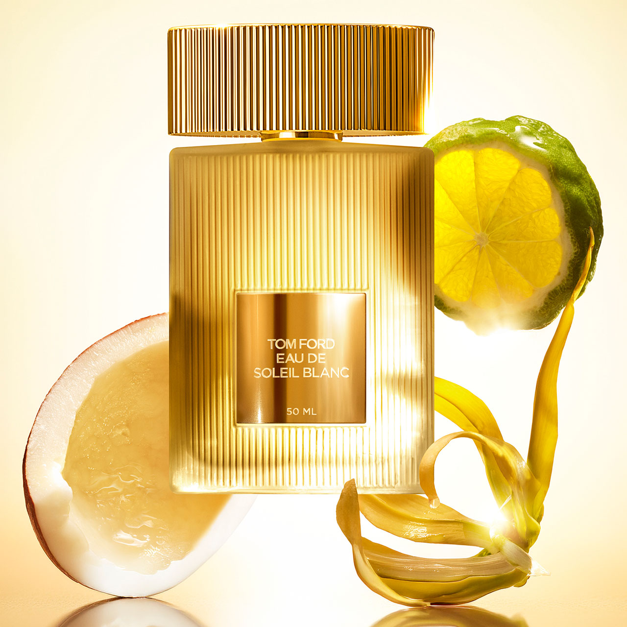 Tom Ford Eau de Soleil Blanc fragrance bottle with gold ridged design, surrounded by lemon and grapefruit slices on pale yellow background
