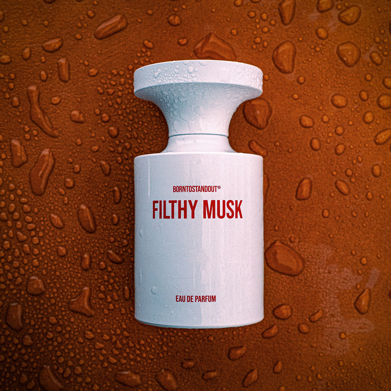 BORNTOSTANDOUT Filthy Musk eau de parfum bottle with white cap against textured bronze background