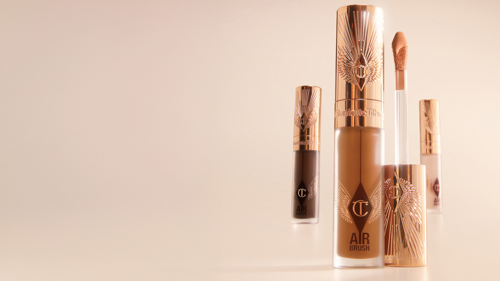 Makeup products with rose gold packaging, including a foundation bottle and lip gloss.