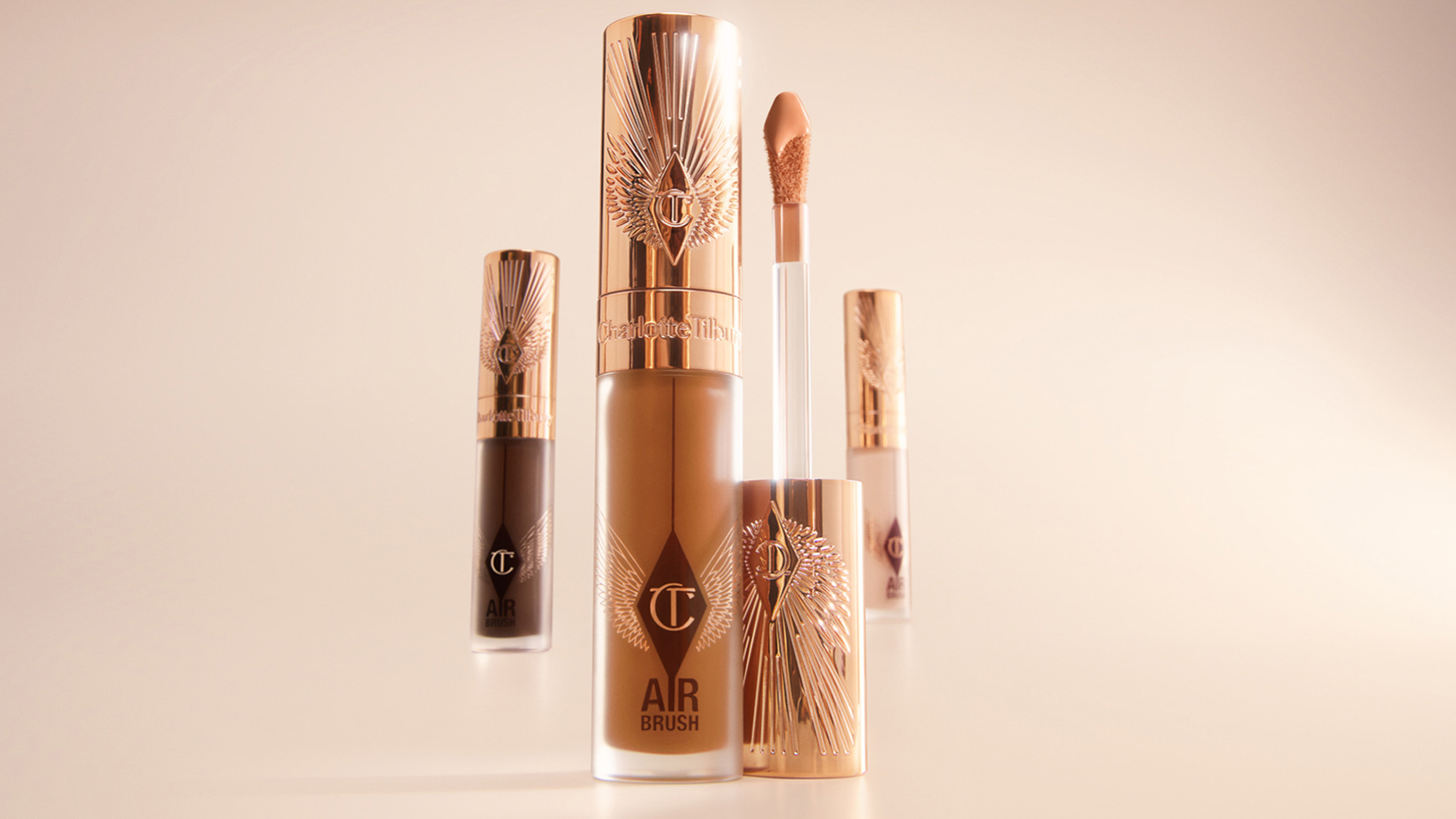 Makeup products with rose gold packaging, including a foundation bottle and lip gloss.