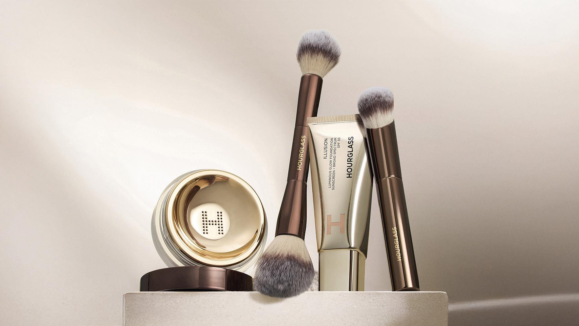 Makeup set with brushes, a tube, and a round compact, all in elegant packaging.