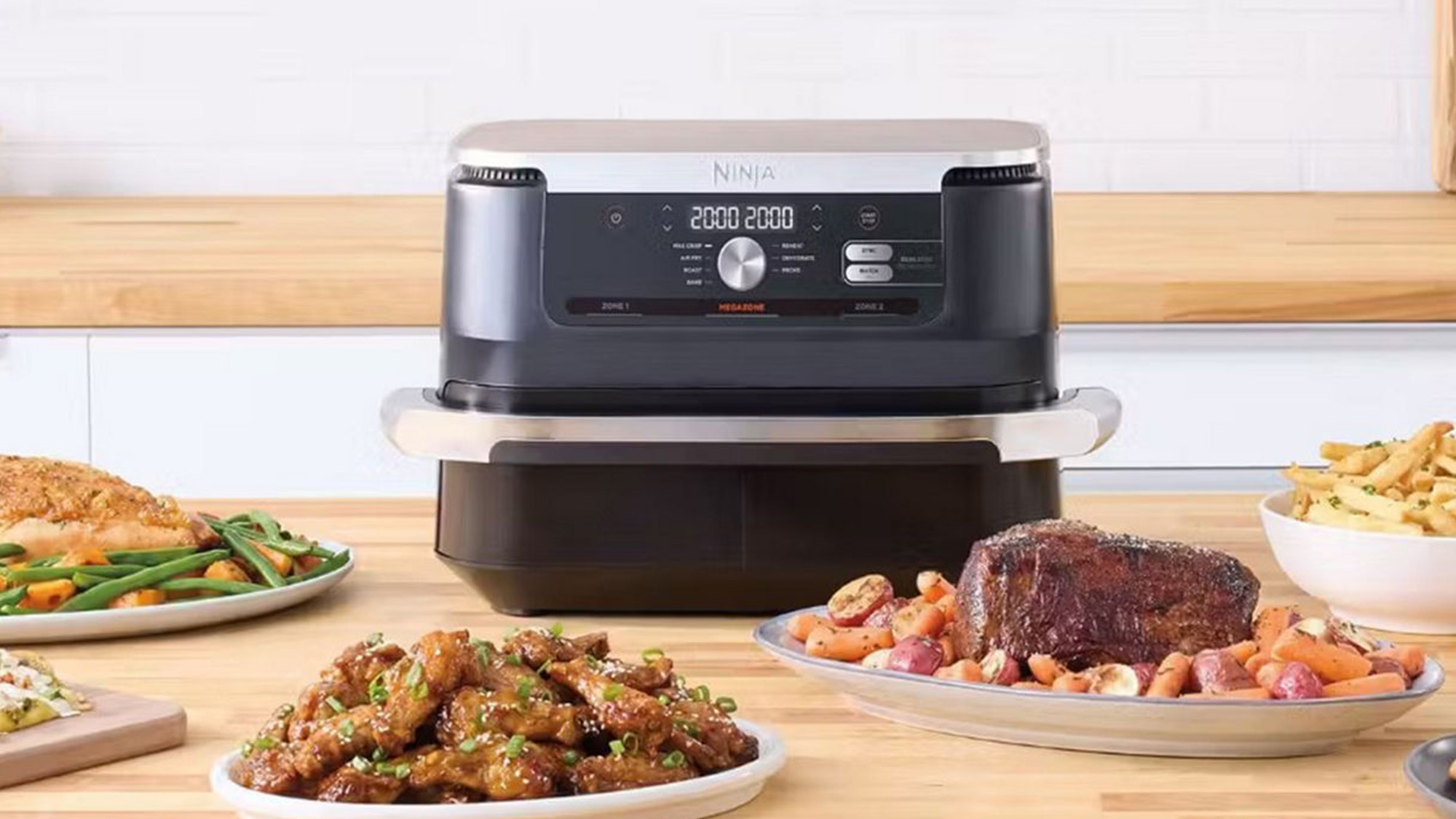 Ninja air fryer surrounded by cooked dishes including roasted chicken, steak with vegetables, fried chicken, chips, and green beans on wooden kitchen counter