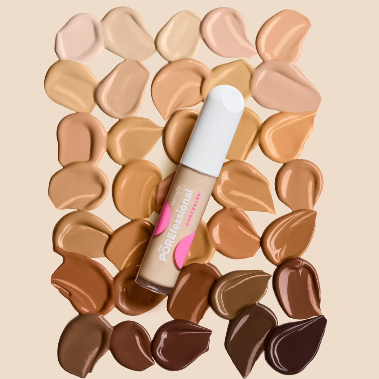 Benefit foundation bottle with pink and white packaging displayed against a palette of foundation shade swatches in various skin tones