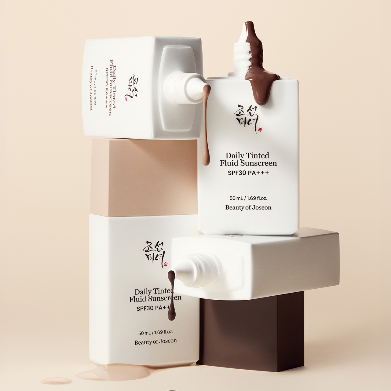 Beauty of Joseon Daily Tinted Fluid Sunscreen bottles with SPF 30 PA+++ displayed on cream and white stacked blocks with product swatches