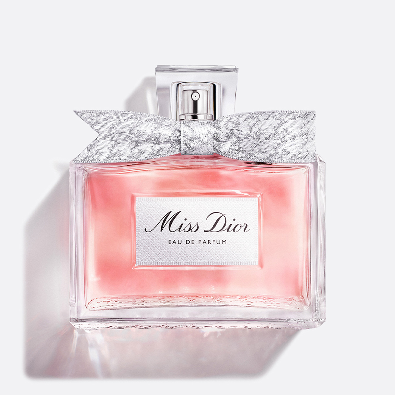 Miss Dior Eau de Parfum bottle with silver sparkle bow against white background