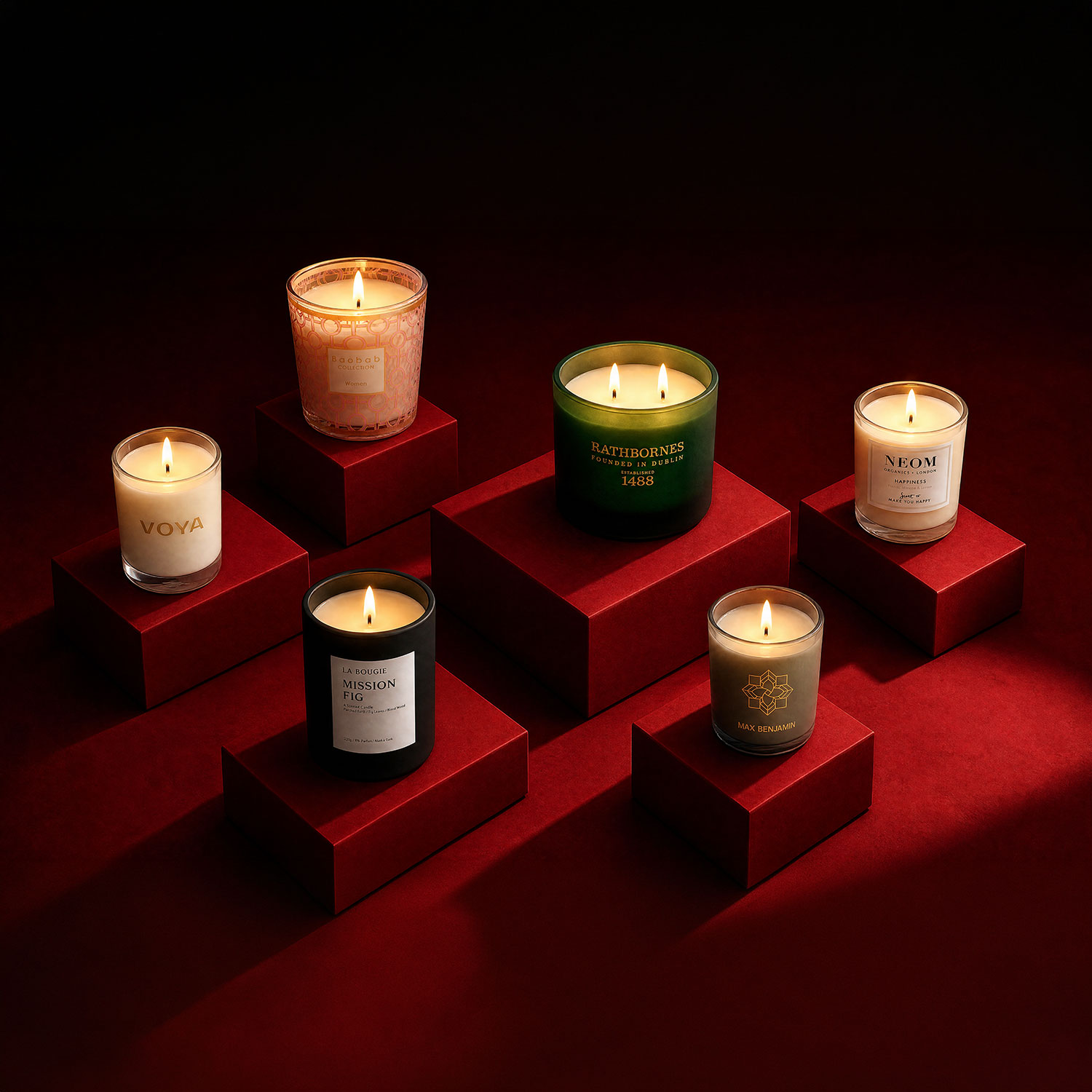 Six luxury scented candles displayed on red blocks: Voya, Rathbornes, Neom, and Max Benjamin branded candles against red background