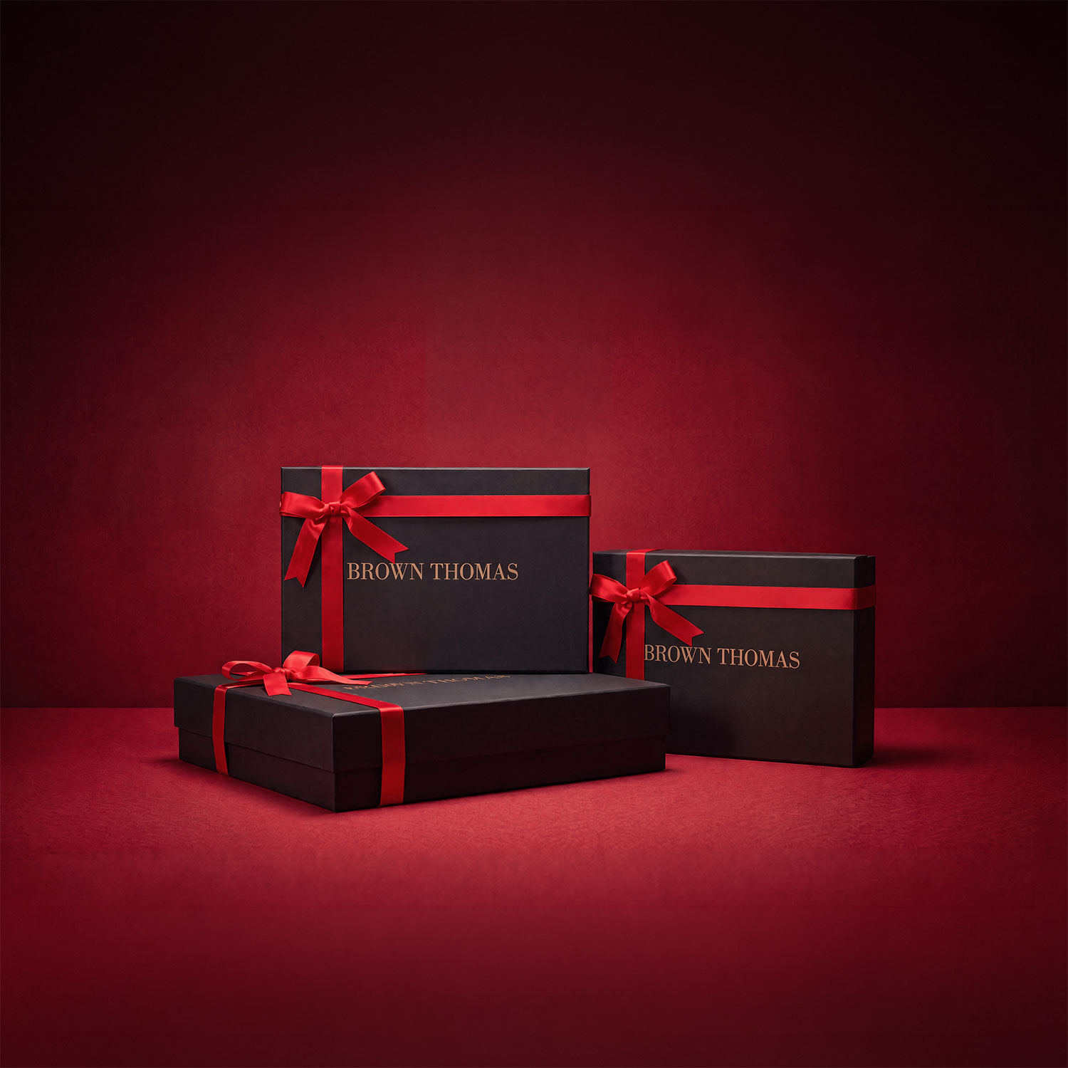 Three black gift boxes with red ribbon bows on red background