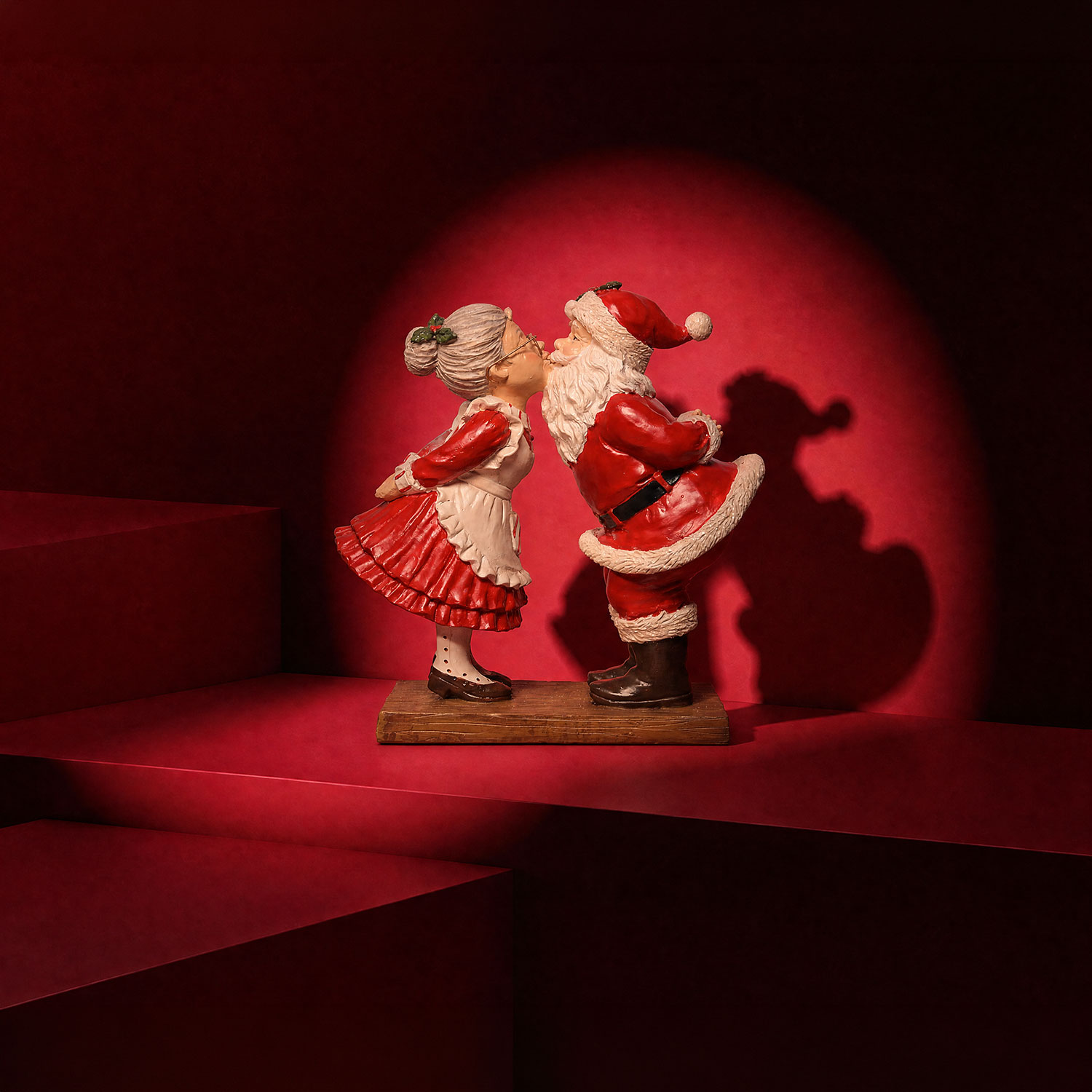 Father Christmas and Mrs Claus figurine ornament in red and cream, kissing under mistletoe on wooden base