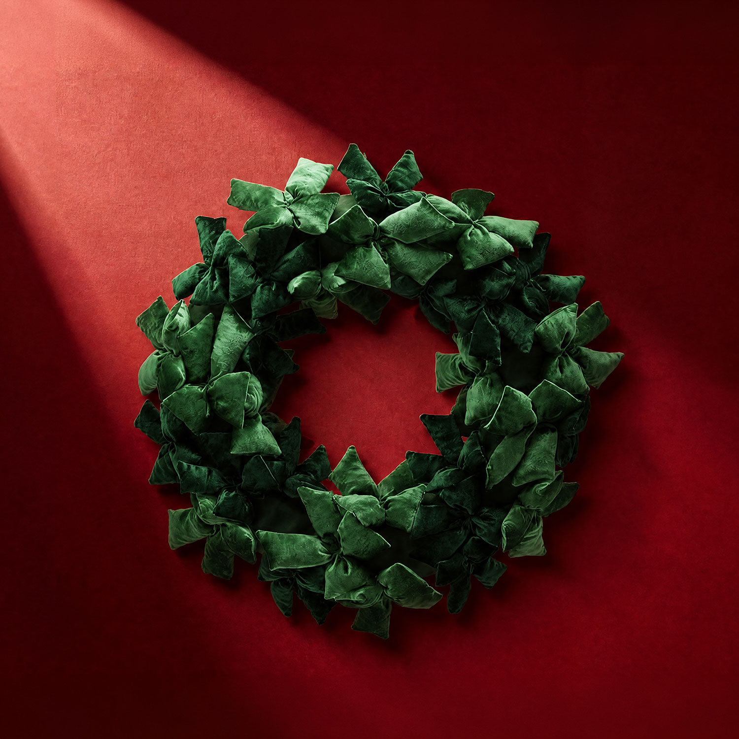 Dense emerald green velvet wreath with clustered bows against a red background
