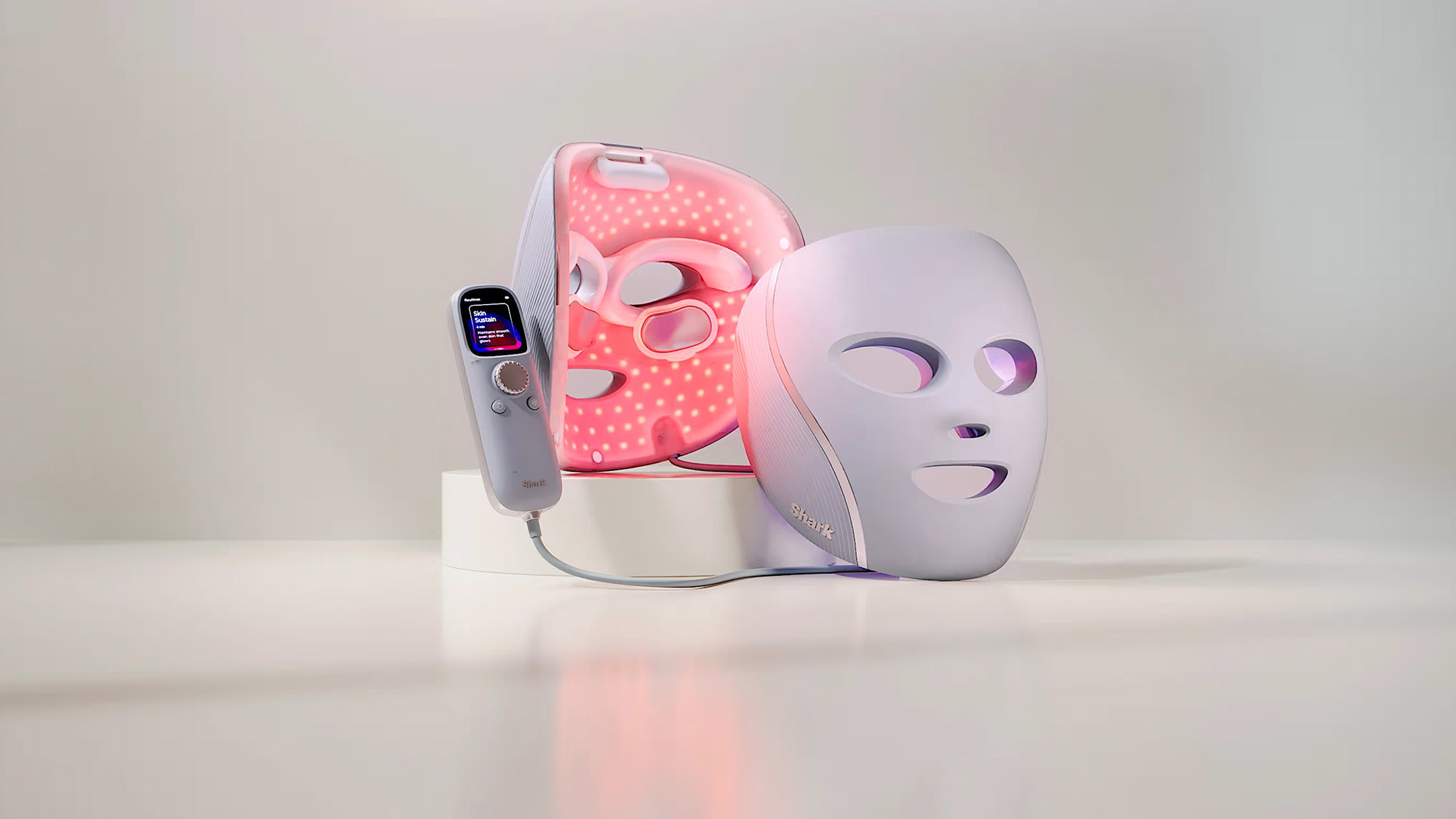 LED light therapy mask in white and pink LED light therapy device with handheld control unit