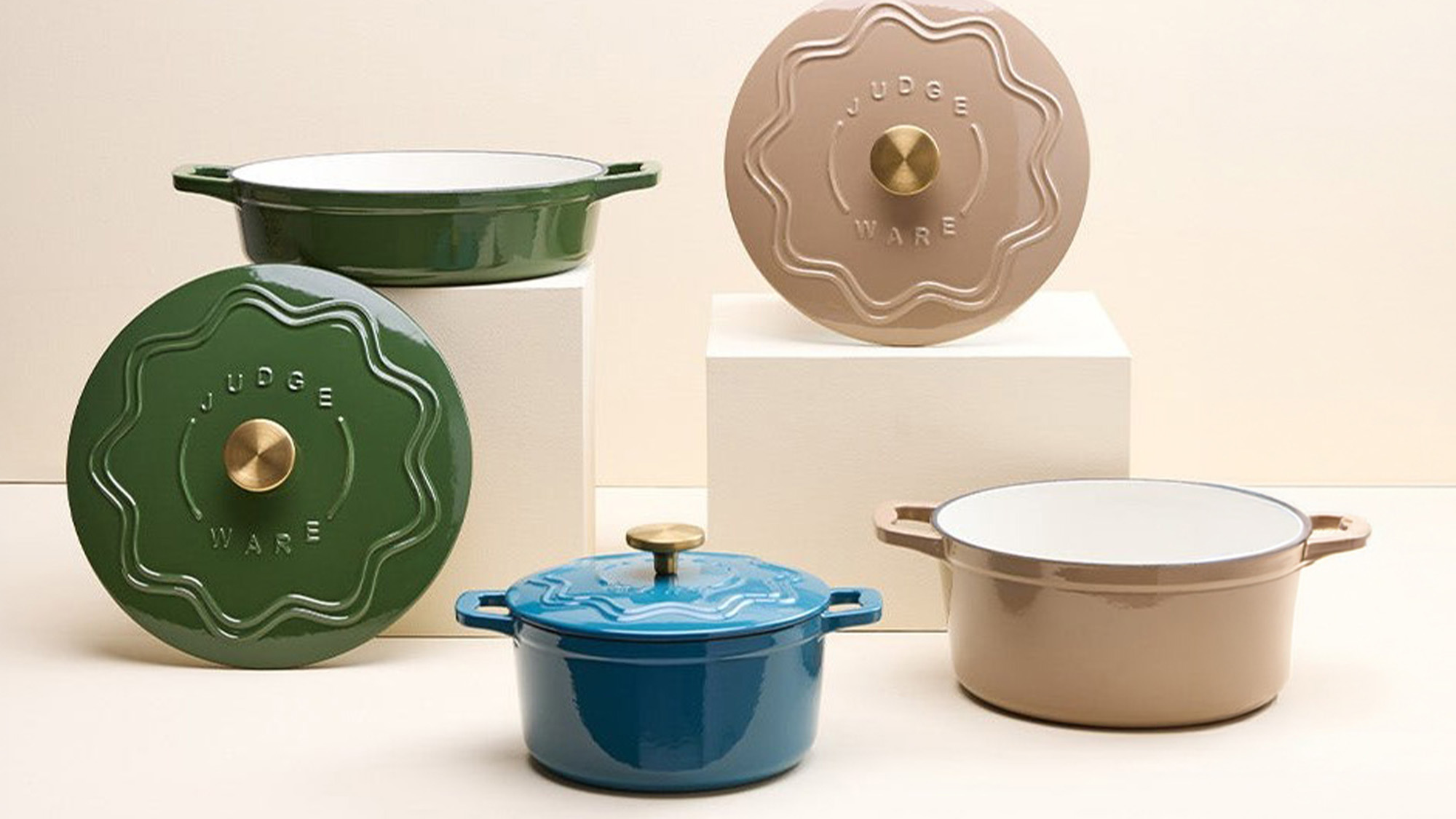 Collection of coloured cast iron cookware including green, blue and taupe casserole dishes with brass knobs