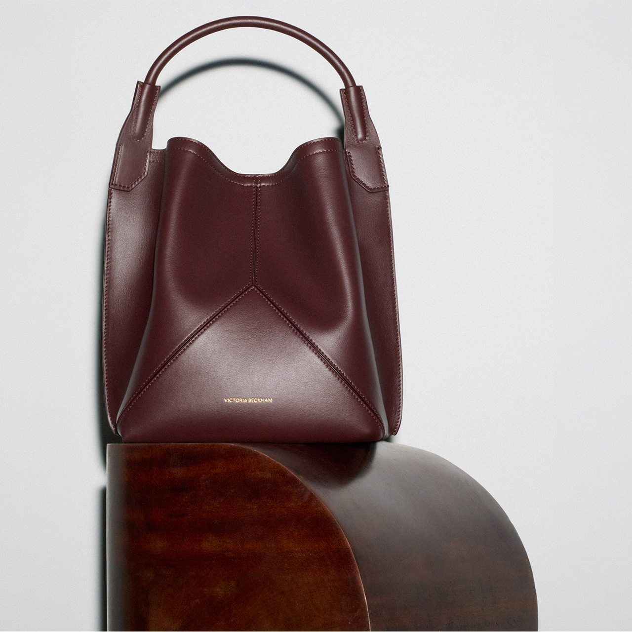 Burgundy leather structured handbag with curved handles displayed on neutral background