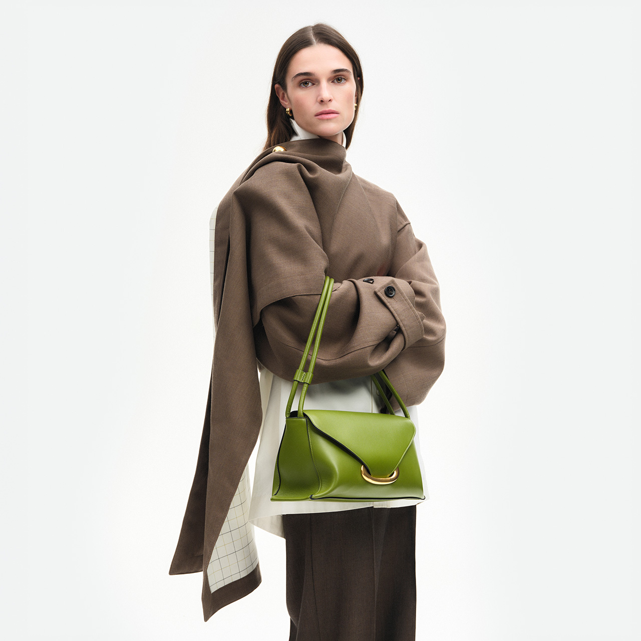 Woman wearing beige coat and black trousers with bright green leather shoulder bag