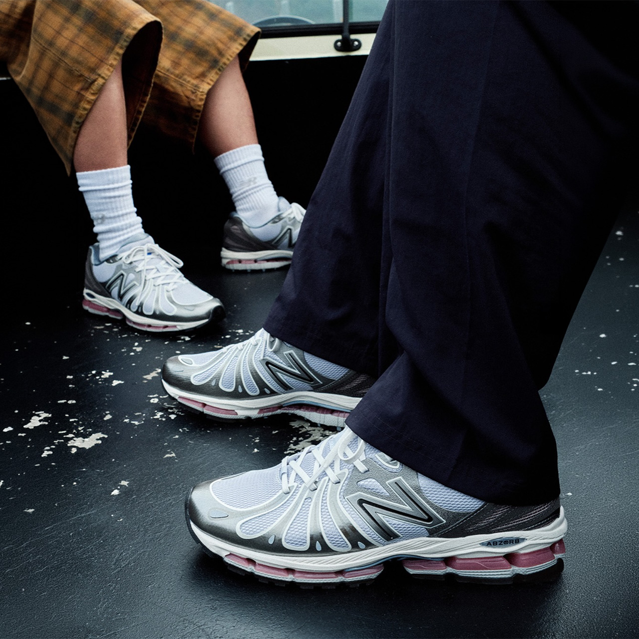 Three people wearing white and grey New Balance trainers with white socks and dark trousers