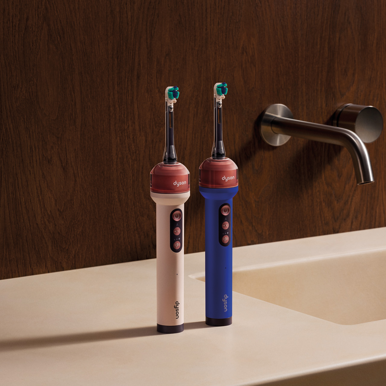 Two Dyson electric toothbrushes in cream and blue with teal brush heads on bathroom sink