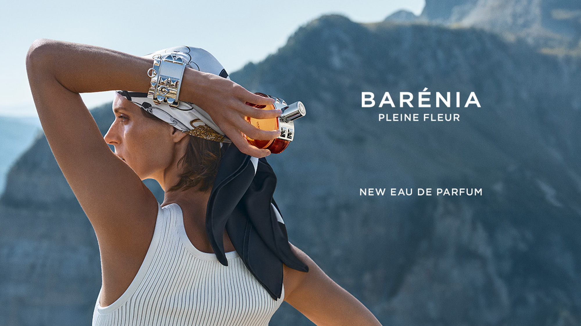 A person in a white tank top holds a perfume bottle, with mountains in the background. Text reads 'BARÉNIA PLEINE FLEUR NEW EAU DE PARFUM.'