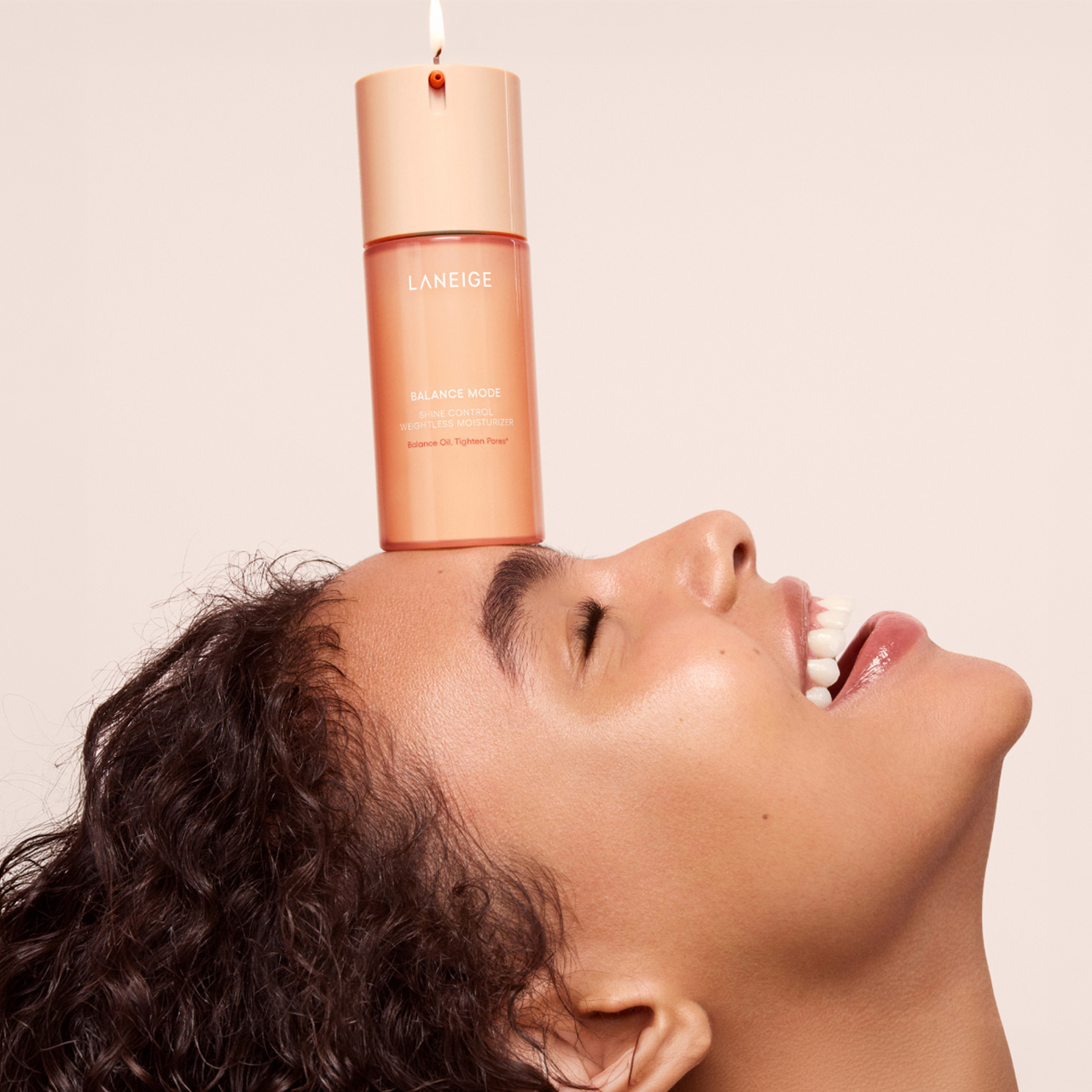 Woman with eyes closed holding Laneige Balance Mode essence oil against her face on neutral background