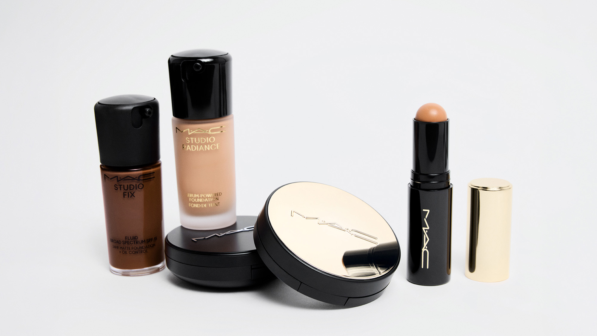 M.A.C makeup collection including foundation, powder, concealer and brushes on light background