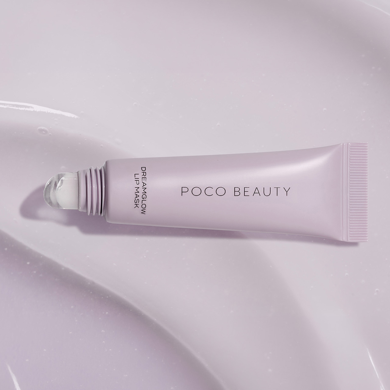 Pale pink tube of Poco Beauty Dreamglow Lip Mask displayed on textured white surface