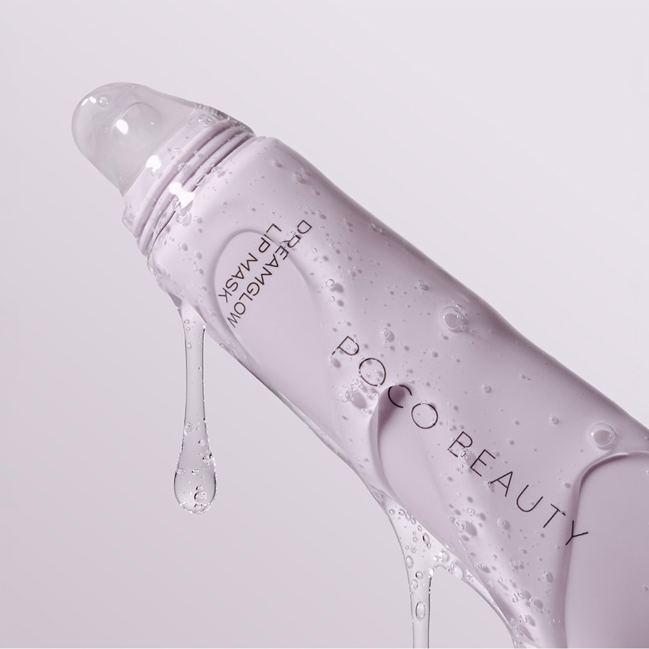 Poco Beauty moisturising lip treatment bottle with liquid droplet on pale background