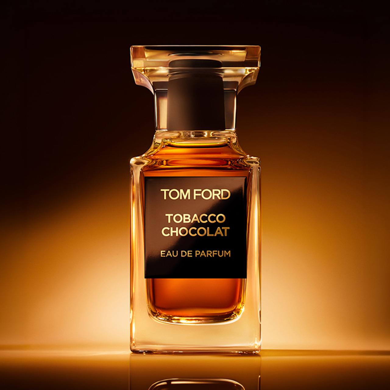 Tom Ford Tobacco Chocolat eau de parfum bottle with amber liquid and gold cap against warm lighting