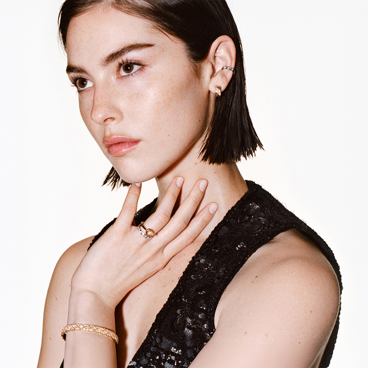 Woman wearing black sleeveless top displaying gold rings and bracelet from fine jewellery collection