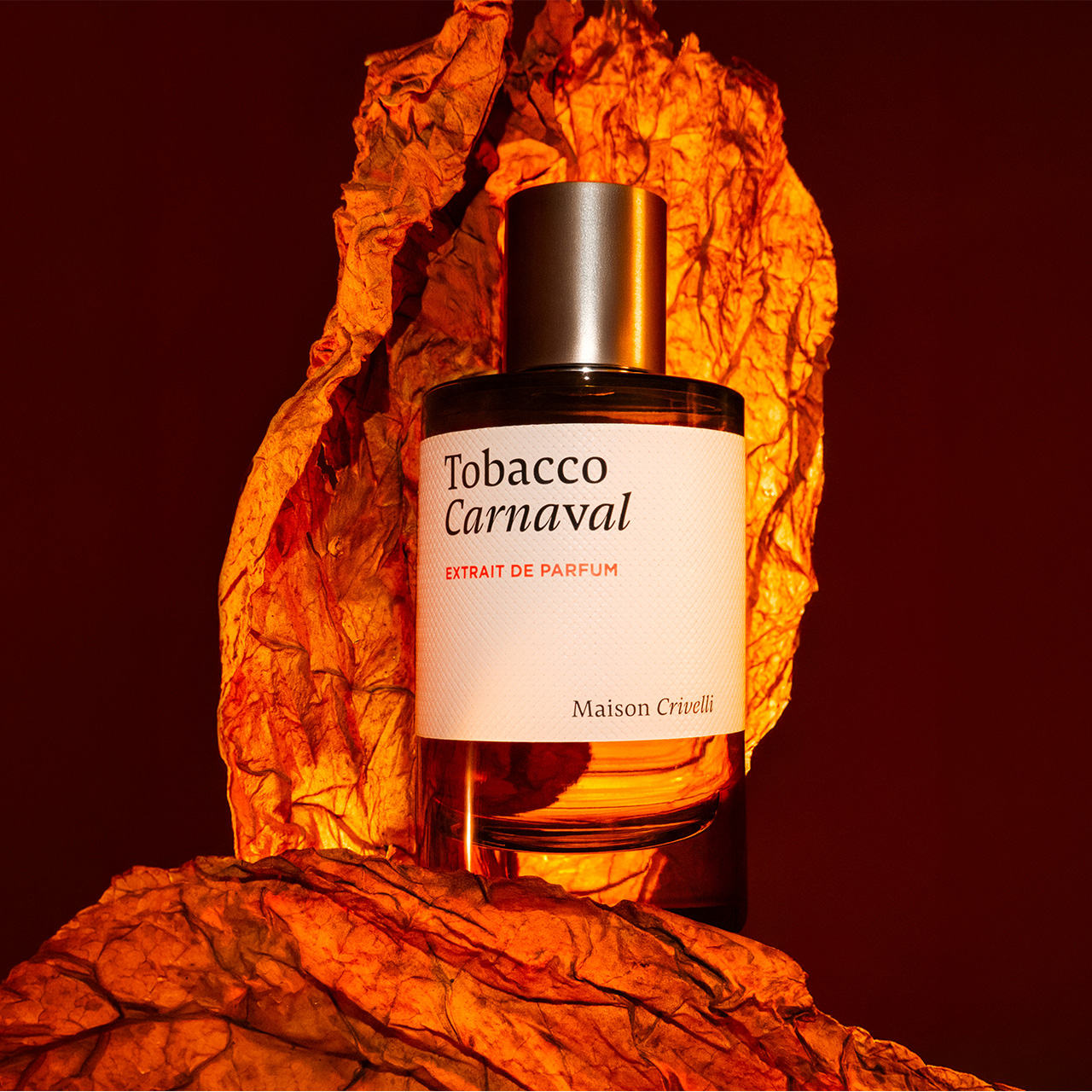 Maison Crivelli Tobacco Carnaval parfum bottle with label displayed against dramatic orange and amber textured background
