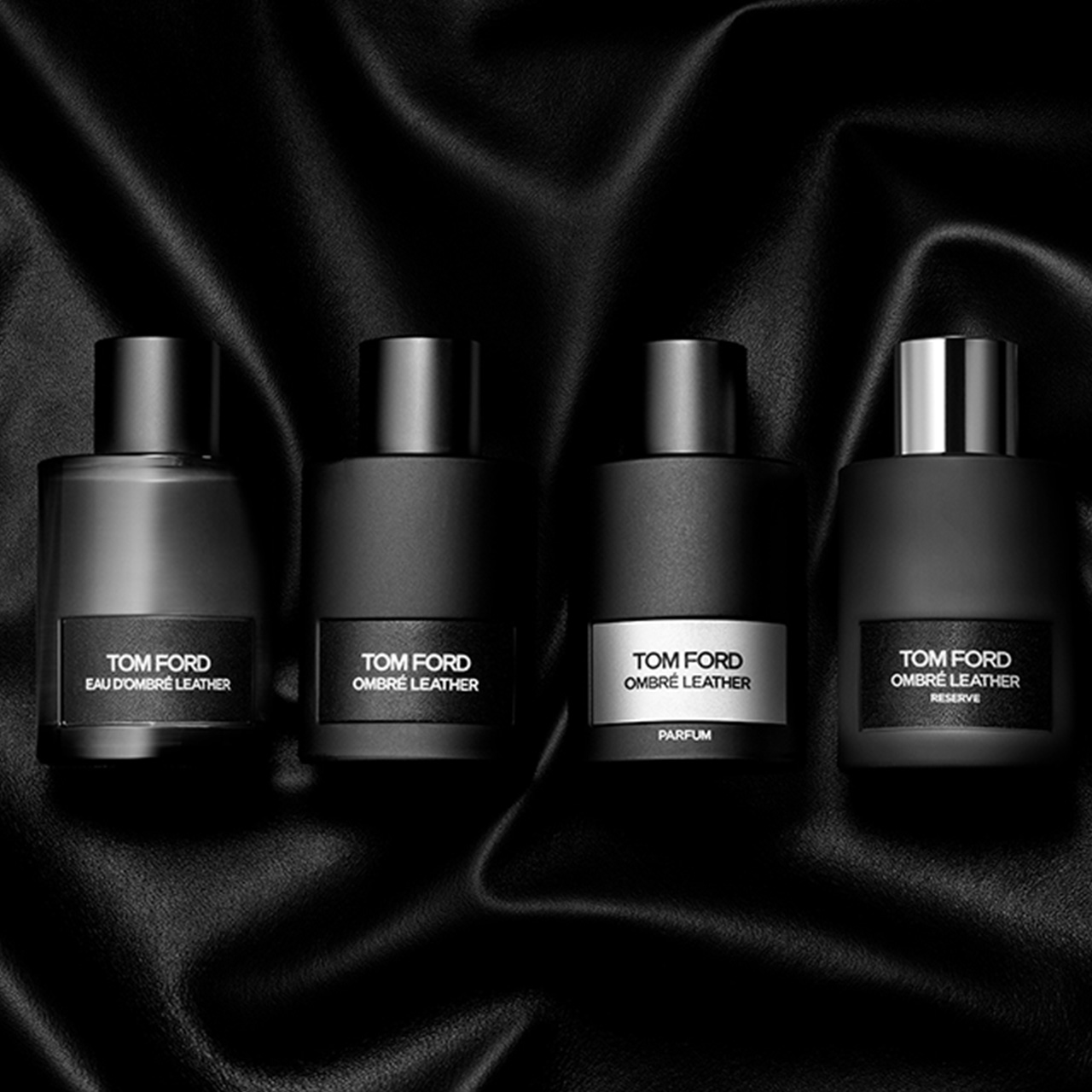 Four Tom Ford Ombr&eacute; Leather fragrances in dark bottles with silver and black labels on textured background