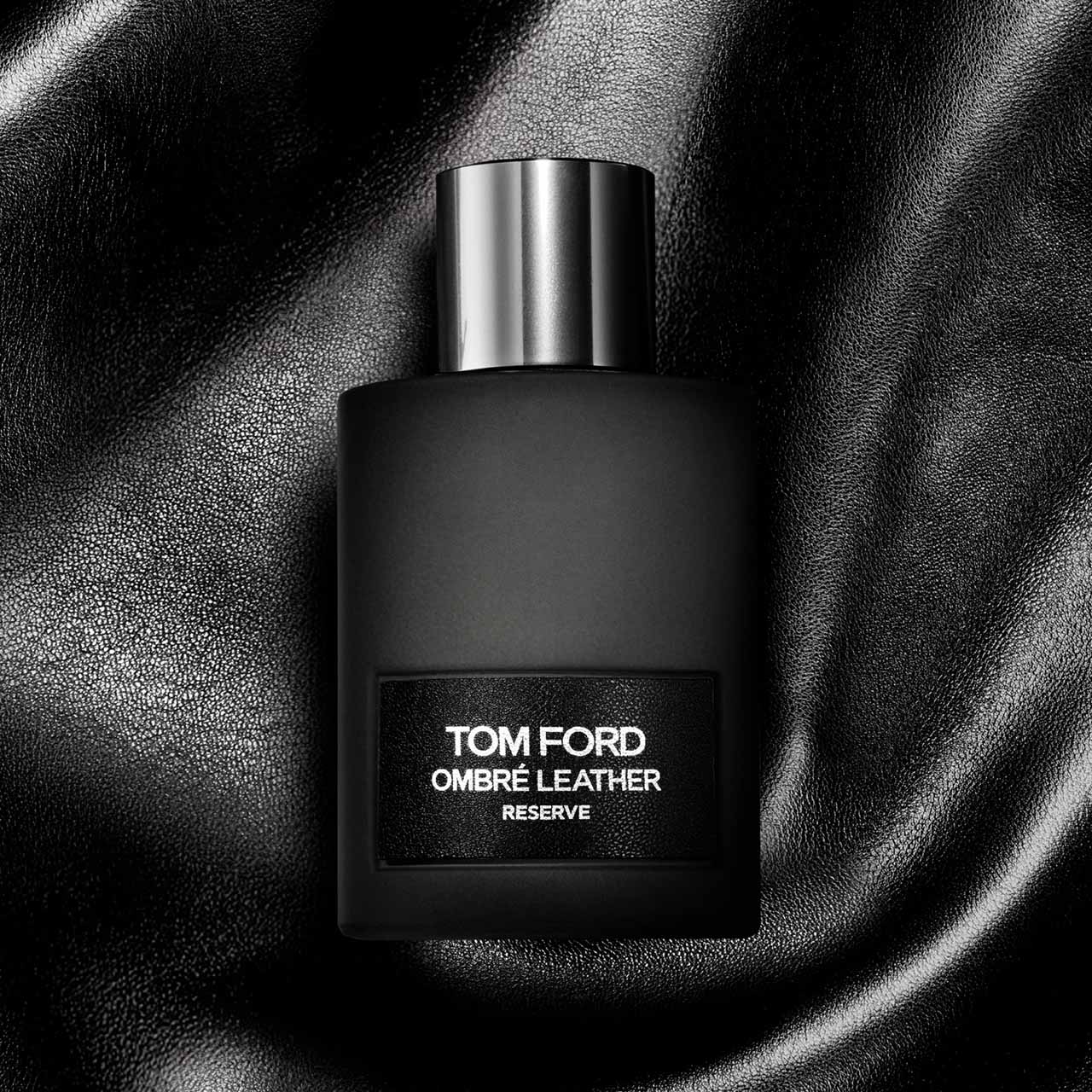 Tom Ford Ombré Leather Reserve black fragrance bottle with silver cap against textured black leather background