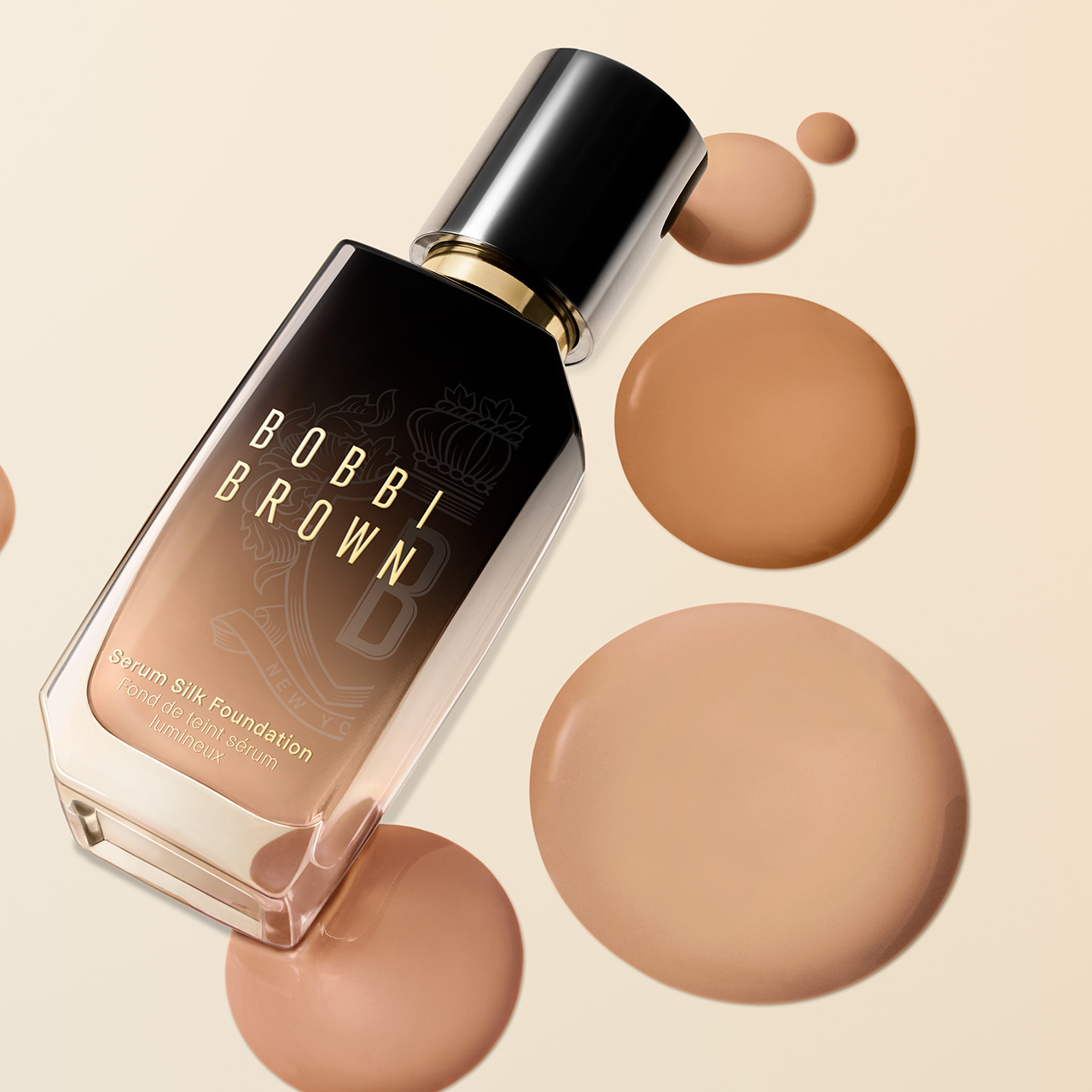 Bobbi Brown Serum Silk Foundation bottle in warm beige tone surrounded by liquid foundation droplets on cream background.