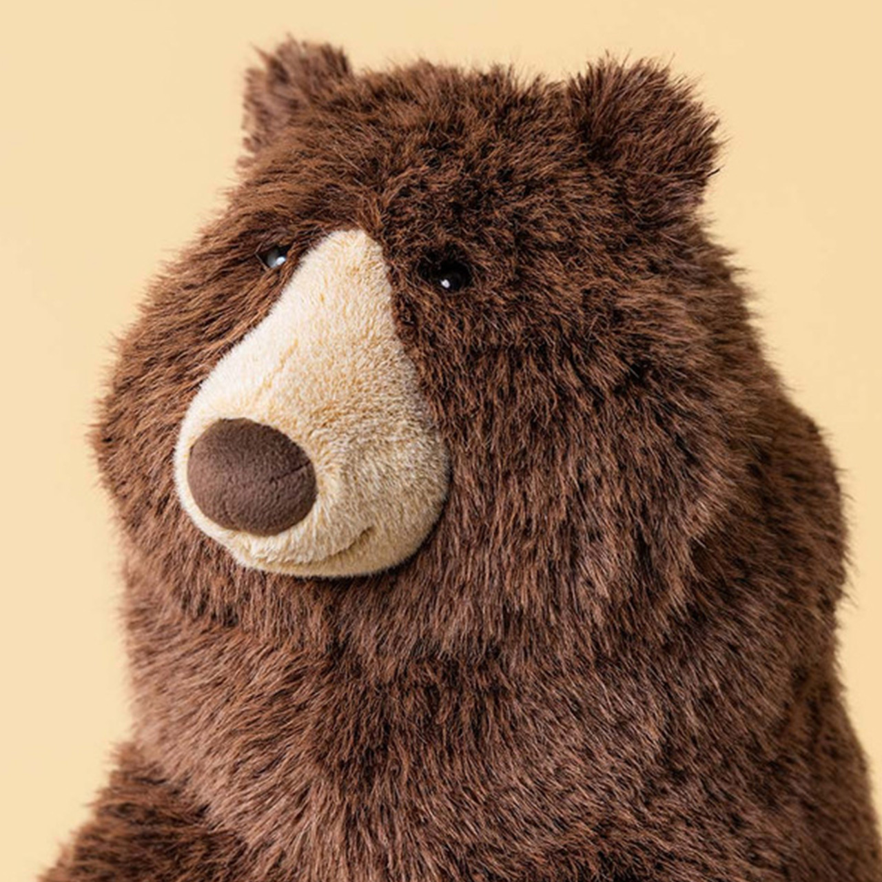 Brown plush bear toy with cream-coloured face against cream background