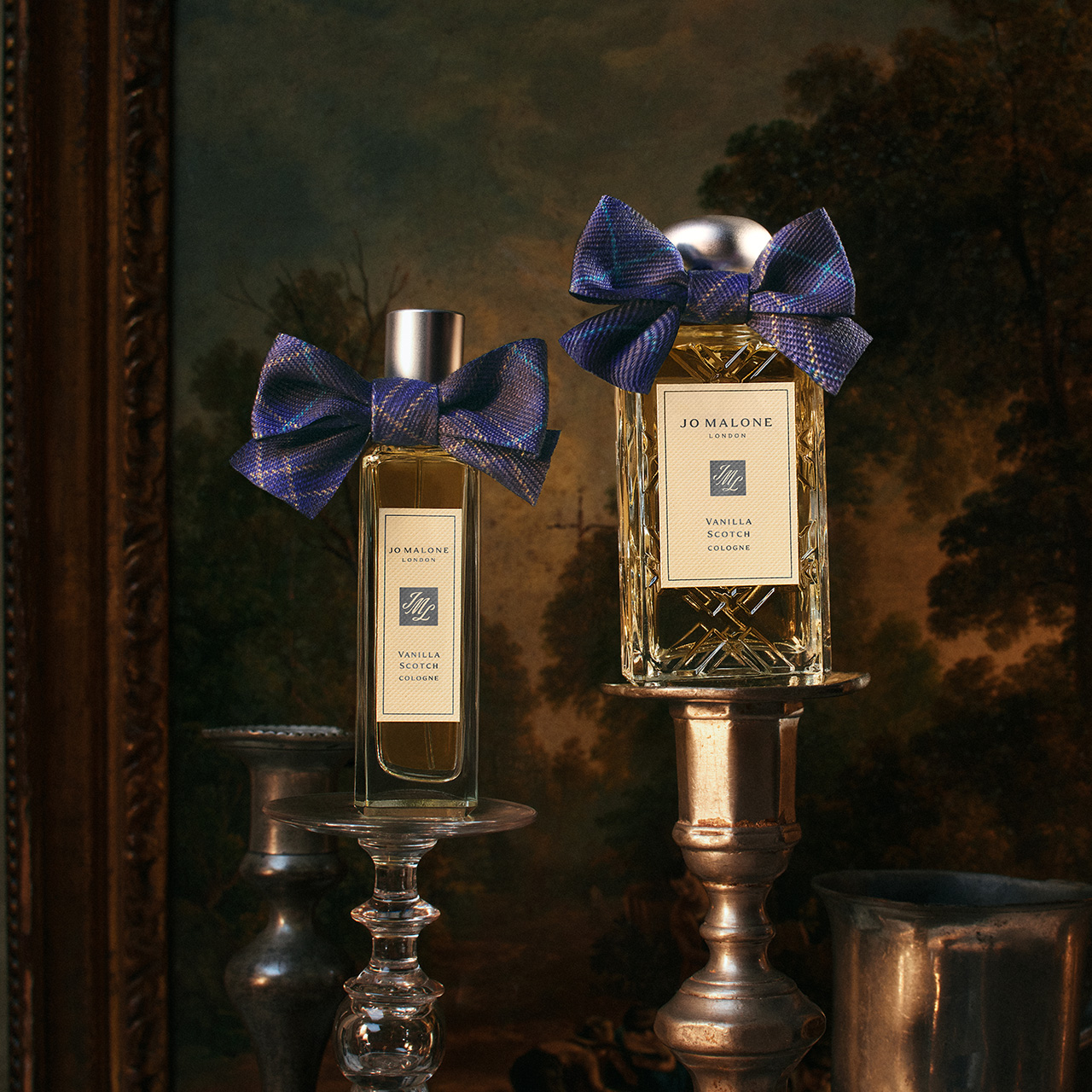 Two Jo Malone Vanilla Scotch cologne bottles with blue tartan bows on ornate stands