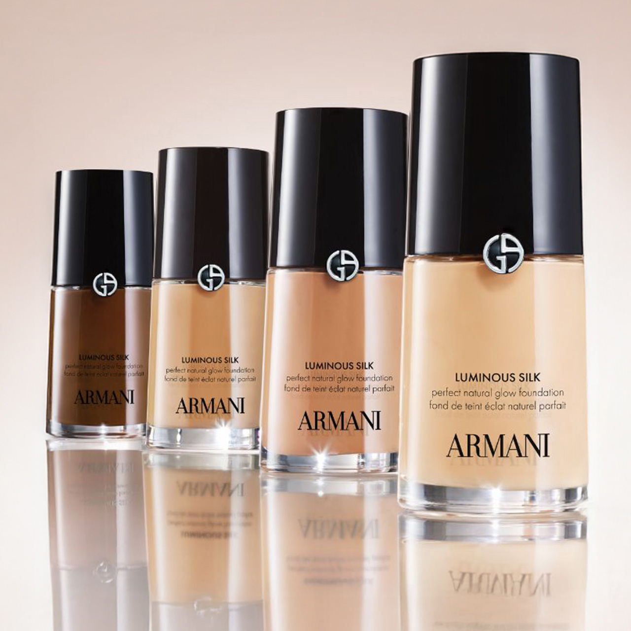Four bottles of Armani Luminous Silk foundation in varying shades are displayed in a row.