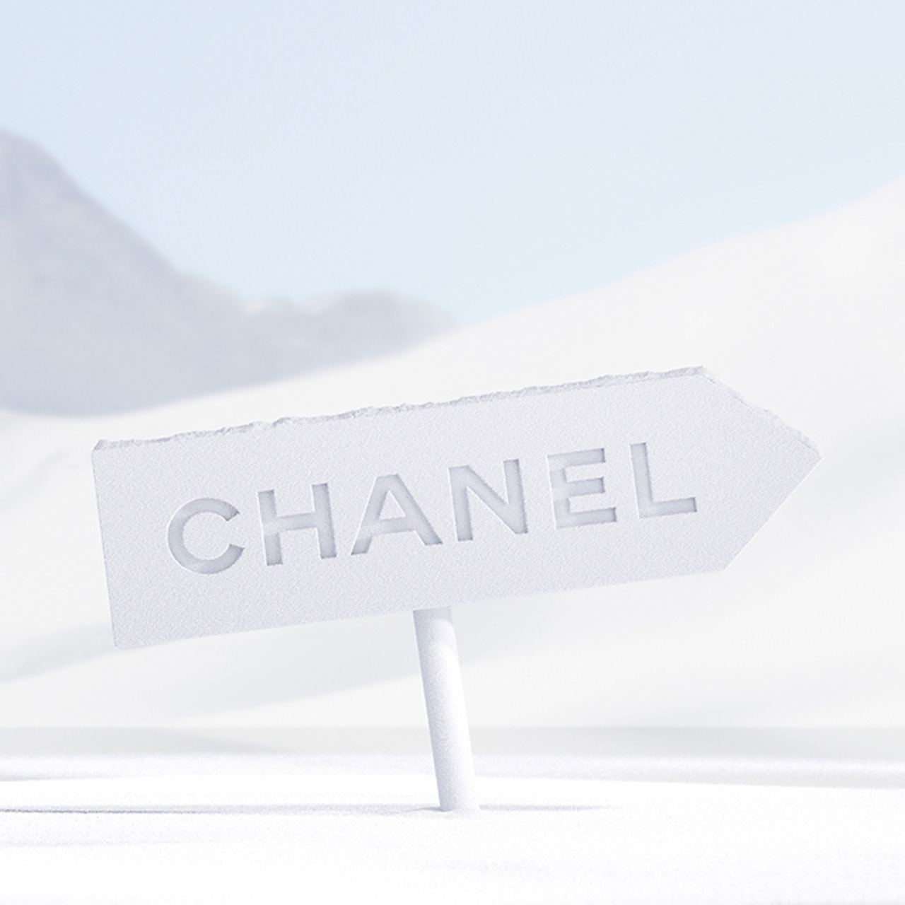 A white arrow sign with 'CHANEL' points against a snowy landscape background.