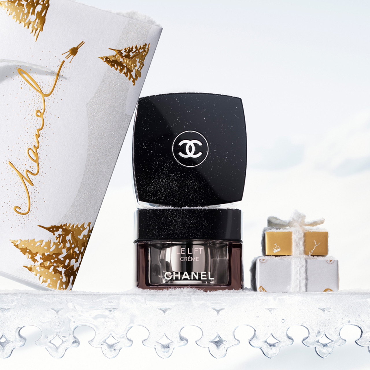 Chanel Le Lift Cr&egrave;me skincare jar with black sparkle container displayed with festive white and gold wrapped gift boxes and decorative wrapping paper