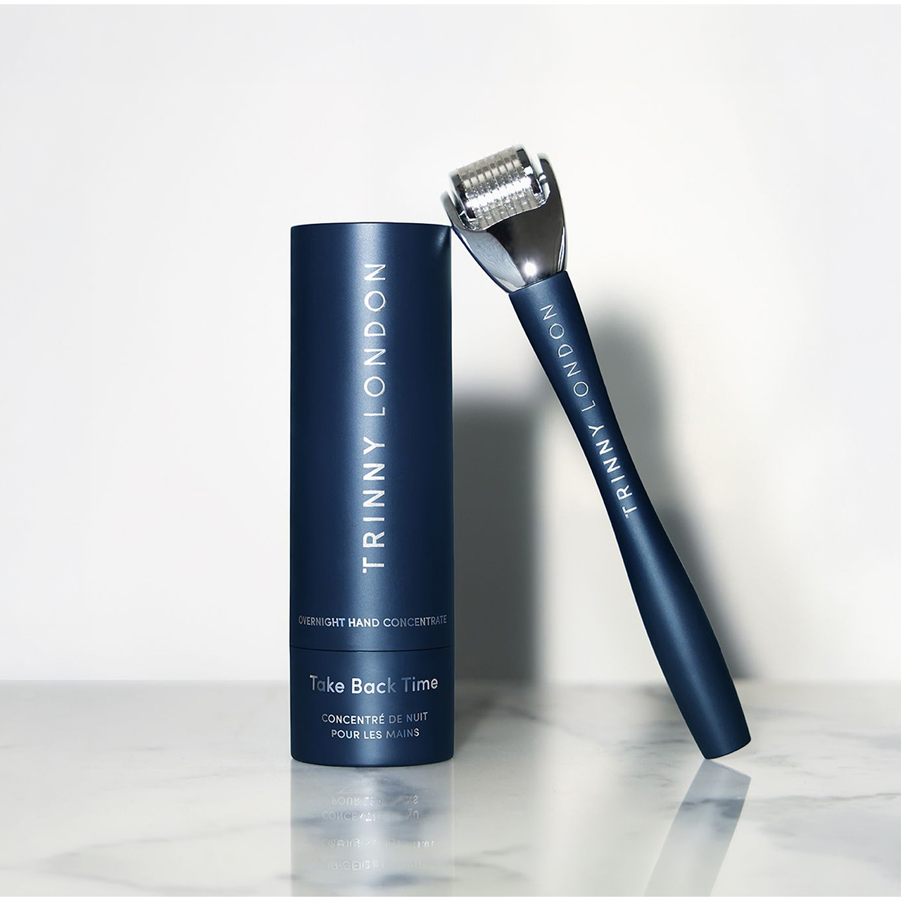 Navy cylindrical packaging for Trinny London overnight hand concentrate with matching dark blue applicator pen